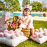 baby, bench, bouquet, child, cute, flowers, footwear, grass, hat, nature, outdoor, park, pillows, pink_clothing, pom_poms, portrait, sunny, toddler, toy, wicker_basket