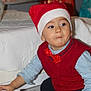 Marius a rejoint le concours — aidez-le/la à gagner de superbes lots ! toddler, child, santa_hat, red_vest, blue_shirt, toy, floor, indoor, person, hand, box, holiday, christmas, gift_wrap, white_shoe, curious, expression, home, tile_floor, festive