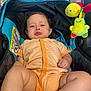 baby, brick_wall, child, clothing, comfort, cute, expression, funny_face, indoor, infant, lighting, onesie, person, plush_toys, pouty_face, seat, small_child, socks, stroller, toy