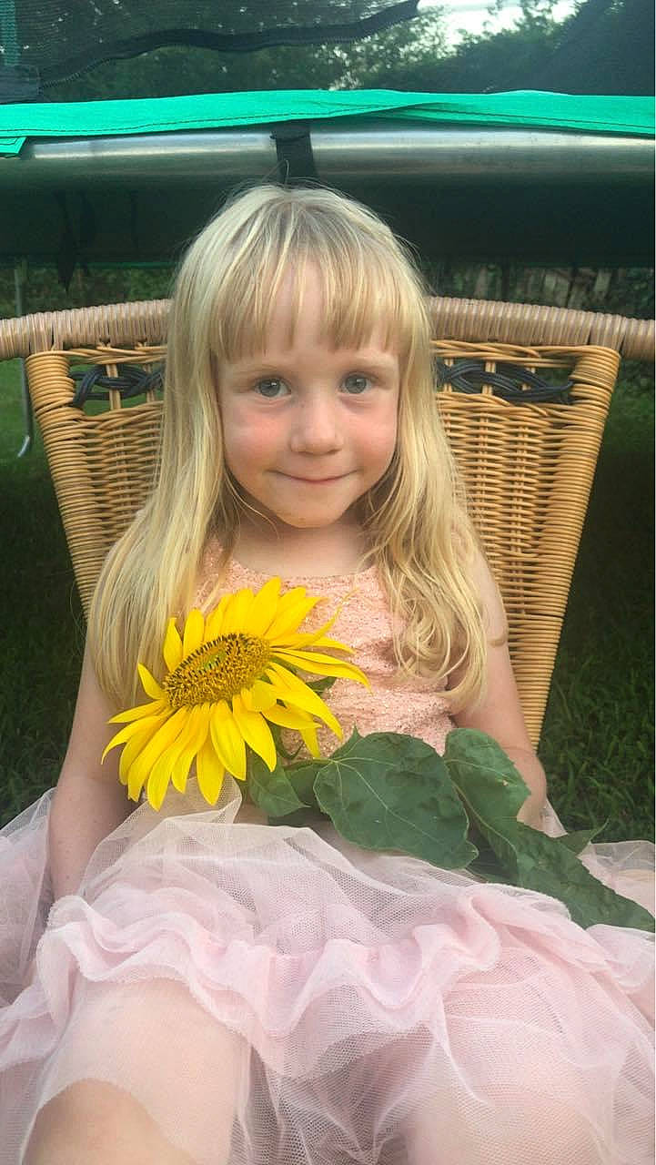 Annalee is registered to the contest to win money with this photo: child, child_model, eye, flower, joy, long_hair, person, plant, smile, sunflower, toddler, yellow