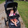 baby, barefoot, bottle, cabin, campground, child, family_outing, grass, jogging_stroller, nature, outdoor, path, pink_clothing, playground, portrait, sitting, smiling, stroller, toddler, tractor