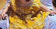 Annabelle is registered to the contest to win money with this photo: baby, child, infant, smiling, laughing, yellow_dress, plaid, bare_feet, seated, portrait, indoors, play_mat, minnie_mouse, cartoon, couch, wood_floor, happy, blond_hair, short_sleeves, photography