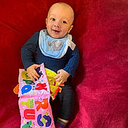 Diantae is registered to the contest to win money with this photo: baby, bed, blanket, clothing, couch, cushion, face, footwear, furniture, head, homedecor, hosiery, pants, person, photography, portrait, quilt, shoe, sitting, sock