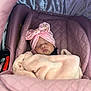 baby, sleeping, blanket, car_seat, pink, headband, bow, face, infant, child, cozy, cute, soft, resting, newborn, wrapped, person, indoors, closeup, peaceful