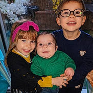 Mateo participe au concours pour gagner de l'argent avec cette photo : child, baby, smiling, glasses, headband, indoor, window, sweater, jeans, happy, family, portrait, cute, toddler, sibling, holding, face, clothing, person, flower