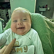Vinnie joined the competition — help win amazing prizes! baby, smiling, indoor, onesie, person, face, hand, furniture, shelf, sink, green_blanket, happy, child, cute, infant, clothing, portrait, home, tickling, cheeks