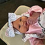 baby, infant, headband, bow, pink_clothing, hand, face, lying_down, cushion, blanket, soft_toys, indoor, child, cute, young, polka_dot, closeup, portrait, newborn, comfort