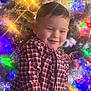 blurred_background, bokeh, boy, candid, cheeks, child, christmas_lights, christmas_tree, festive, green, happy, holiday, indoors, ornaments, plaid_shirt, portrait, red, short_hair, smiling, warm_lighting