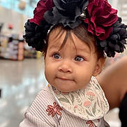 Xareni joined the competition — help win amazing prizes! baby, bib, black_flowers, blurred_background, child, clothing, curious_expression, cute, face, floral_headband, headwear, indoor, person, portrait, public_space, red_flowers, soft_lighting, sweater, toddler, young_child