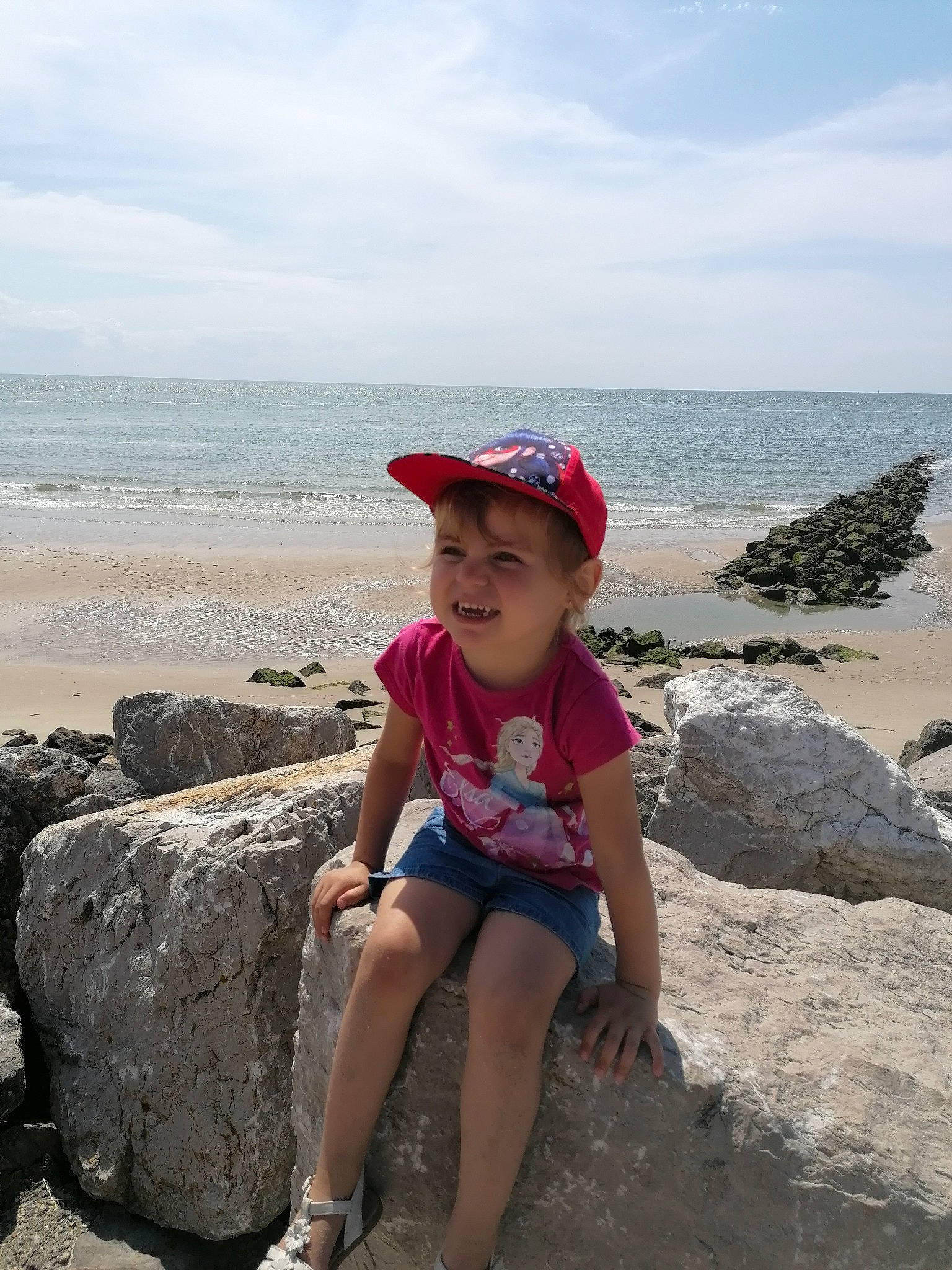 Lena participe au concours pour gagner de l'argent avec cette photo : azure, baseball_cap, beach, cap, cloud, coastal_and_oceanic_landforms, goggles, happy, hat, headgear, horizon, joy, landscape, leisure, person, shorts, sky, summer, sunglasses, toddler