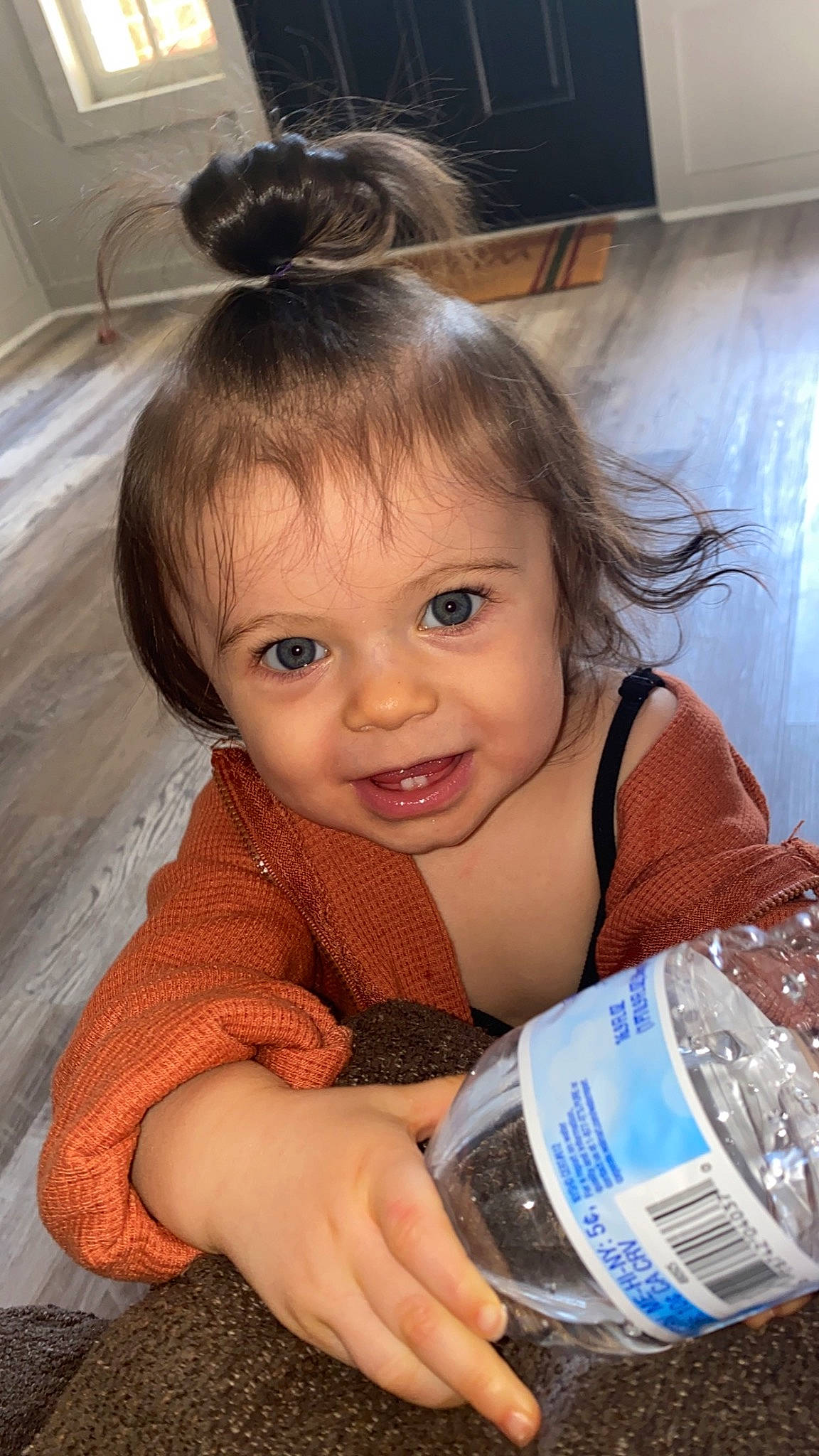 Saylor is registered to the contest to win money with this photo: bangs, bottle, bottled_water, distilled_water, drink, drinking_water, drinkware, ear, eyelash, flooring, hairstyle, happy, iris, mineral_water, organ, person, plastic_bottle, skin, smile, toddler