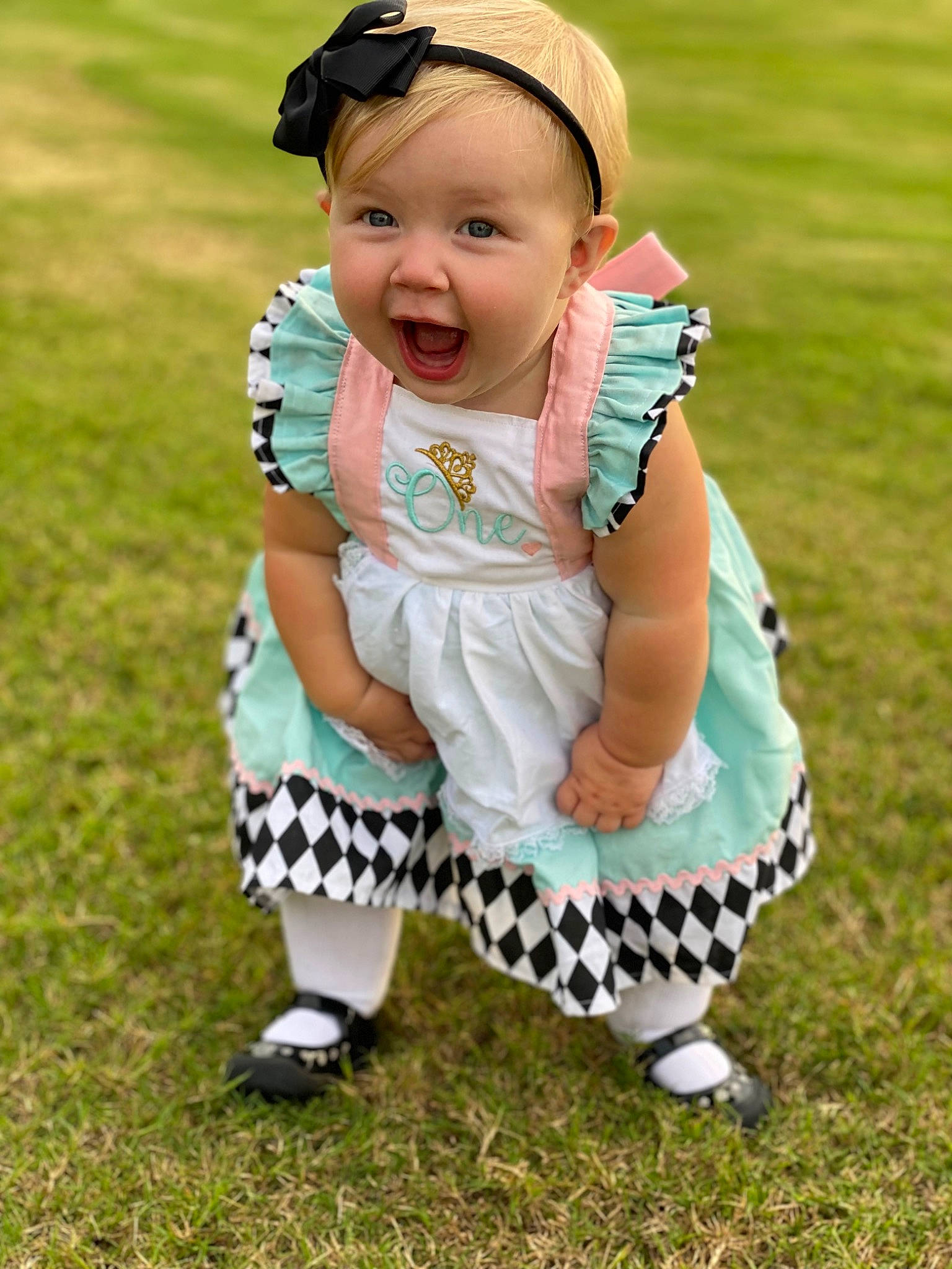 Mckinley joined the competition — help win amazing prizes! baby, baby_toddler_clothing, dress, face, footwear, fun, grass, grassland, green, happy, hat, head, pattern, people_in_nature, person, recreation, sitting, sleeve, smile, sneakers