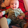 Kaiden is registered to the contest to win money with this photo: baby, child, smiling, green_striped_outfit, indoor, person, adult, red_clothing, tattoo, face, seated, cozy, comfort, soft_lighting, blanket, footwear, hand, legs, closeup, portrait