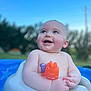 baby, child, smiling, toy, water, pool, outdoor, blue_sky, plastic_seat, happy, cute, infant, playful, summer, nature, background_blur, skin, expression, holding, daylight