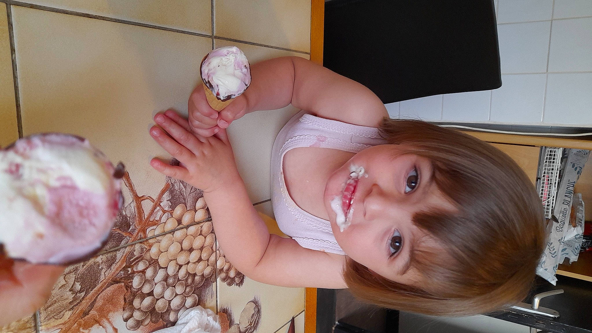 Leana participe au concours pour gagner de l'argent avec cette photo : baby, baby_toddler_clothing, chair, child, dress, finger, food, gesture, happy, human_leg, joy, nail, peach, person, pink, room, skin, smile, sweetness, tableware