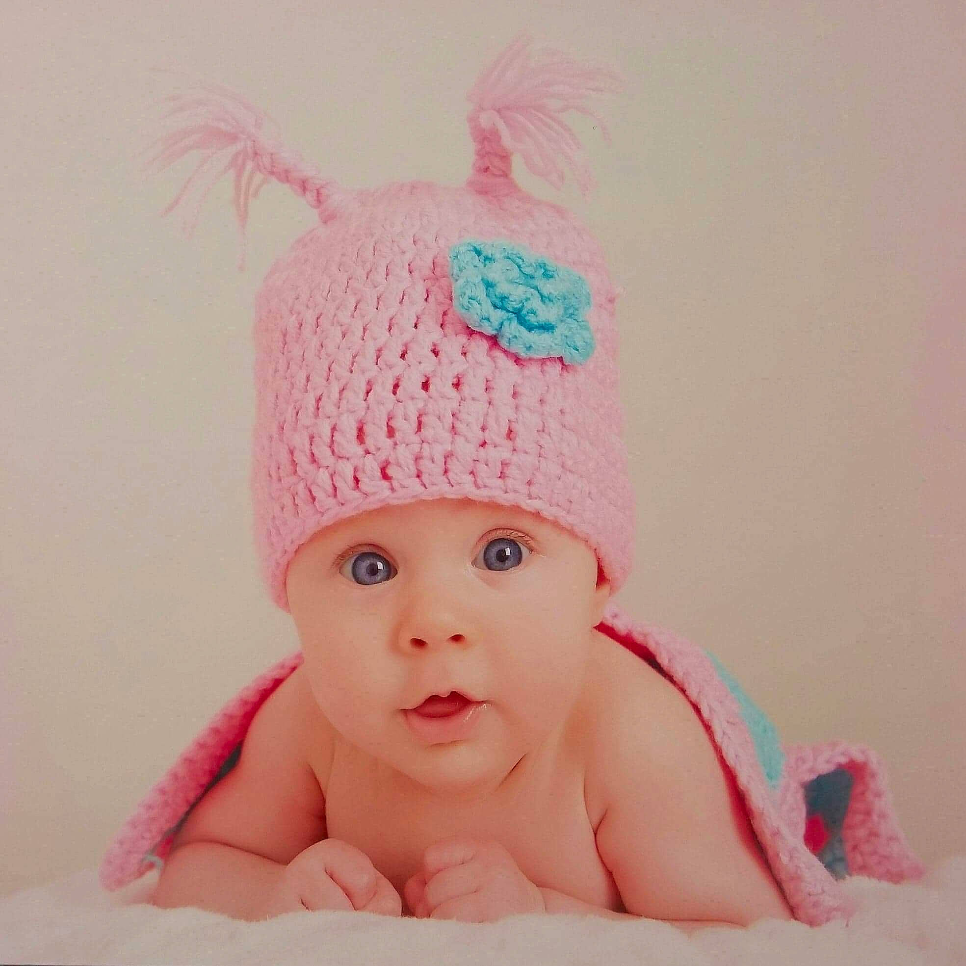 Luana participe au concours pour gagner de l'argent avec cette photo : baby, beanie, bonnet, cap, child, clothing, costume_accessory, costume_hat, crochet, ear, fashion_accessory, hat, headgear, headwear, knit_cap, person, pink, surprise, toddler