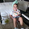toddler, child, smile, happy, face, clothing, headwear, turban, shoes, sneakers, chair, cushion, grapes, fruit, device, tablet, indoor, person, casual, home