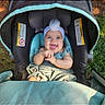 baby, stroller, smiling, happy, headband, outdoor, grass, infant, clothing, child, seat, sunlight, cute, person, portrait, baby_clothes, headwear, playful, young_child, daylight