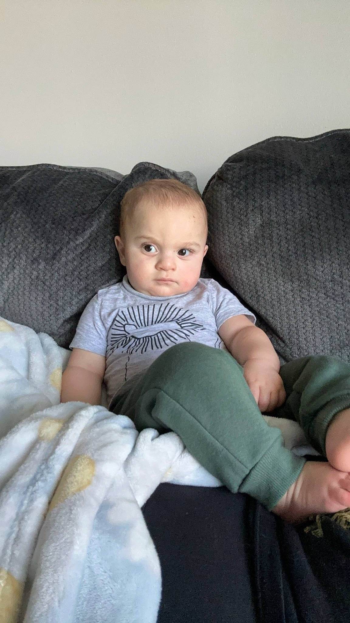 Gene is registered to the contest to win money with this photo: baby, baby_toddler_clothing, cheek, child, comfort, couch, eye, flash_photography, foot, human_leg, knee, lap, leg, linens, pattern, person, sitting, sleeve, sock, thigh