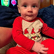 Leon joined the competition — help win amazing prizes! baby, child, infant, red_clothing, pajamas, gnomes, holiday_theme, indoor, person, face, hand, expression, couch, blanket, background, television, cartoon, colorful, cute, seated