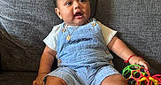 Alex joined the competition — help win amazing prizes! baby, blanket, child, clothing, colorful, couch, denim_overalls, footwearless, furniture, hand, happy, indoor, infant, person, playing, portrait, relaxing, seat, smiling, toys