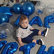 Liam joined the competition — help win amazing prizes! balloons, birthday, blue_balloons, carpet, celebration, child, clothing, curious, face, footwear, home, indoor, letters, party, person, shirt, shorts, sitting, toddler, transparent_balloons