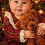 baby, celebration, child, christmas_lights, christmas_tree, cozy, cute, decorations, face, festive, hands, holiday, indoors, infant, plaid_dress, portrait, red_bow, smiling, teddy_bear, warm_lighting