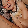 arm, blanket, child, closeup, curly_hair, digital_sticker, fabric, face, happy, indoor, kiss_marks, laughing, person, playful, skin, sleeveless_shirt, smiling, tattoo, tattooed_arm, toddler