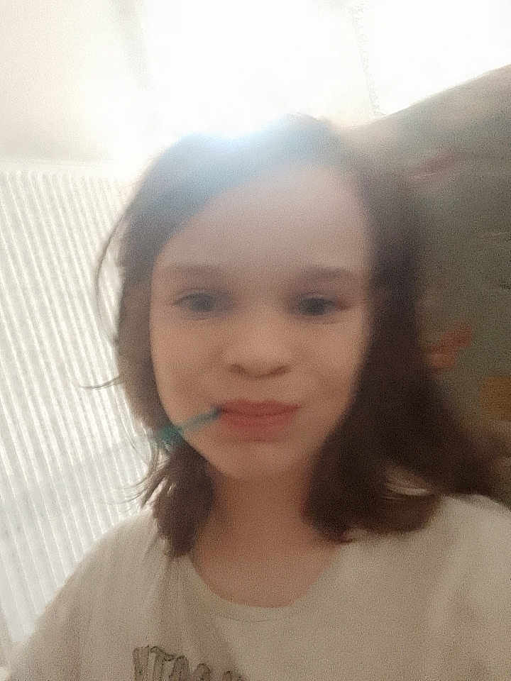 Rose participe au concours pour gagner de l'argent avec cette photo : child, girl, face, smile, selfie, blurry, indoors, toothbrush, hair, portrait, tshirt, window_light, backlit, radiator, young_person, mouth, eyes, cheek, casual_clothing, wallpaper