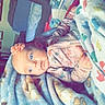baby, blanket, flower_headband, indoor, infant, person, portrait, cozy, soft_texture, furniture, table, bottle, household_items, curious, child, clothing, patterned_blanket, resting, cute, head