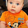 Emiliano is registered to the contest to win money with this photo: baby, infant, child, portrait, wide_eyes, blue_eyes, orange_outfit, mickey_mouse, basketball, cartoon, smiling, indoor, sitting, close_up, face, head, family_photo, clothing, text_overlay, colorful