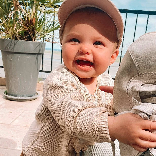 Maggy participe au concours pour gagner de l'argent avec cette photo : baby, baby_toddler_clothing, cap, chin, face, finger, flowerpot, gesture, grass, happy, hat, headwear, houseplant, lip, nose, outerwear, person, plant, skin, sleeve