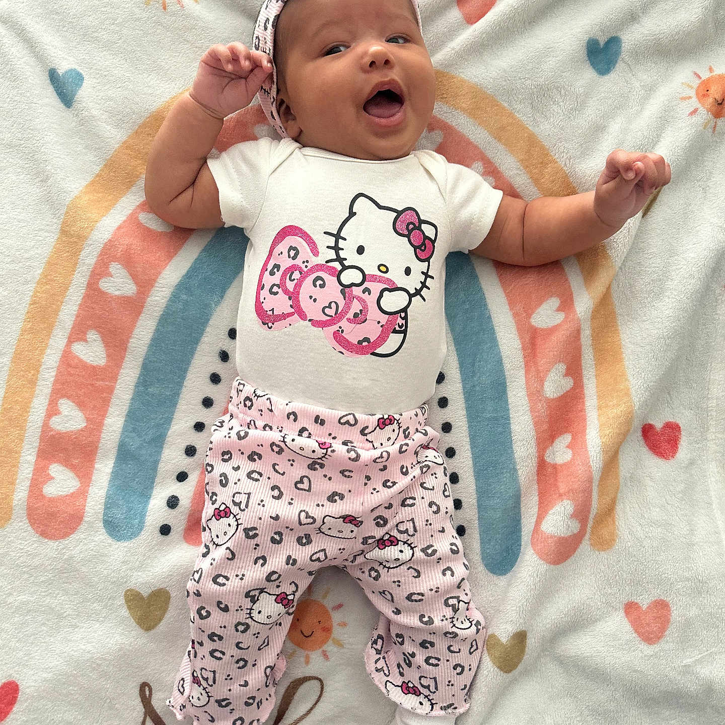 Nalani joined the competition — help win amazing prizes! baby, infant, child, blanket, rainbow, heart, hello_kitty, clothing, headband, smile, happy, cute, playful, toddler, pattern, fabric, lying_down, indoors, soft, colorful