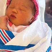 Nalani is registered to the contest to win money with this photo: newborn, baby, sleeping, blanket, pink_hat, infant, cozy, wrapped, peaceful, face, skin, hand, cute, closeup, indoors, resting, child, portrait, soft, warm