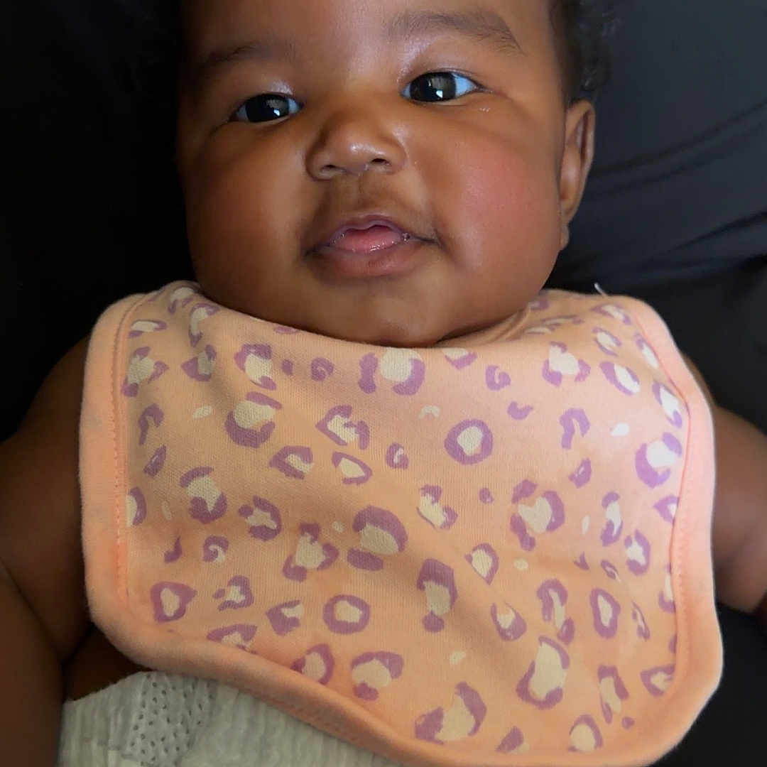 Novèn is registered to the contest to win money with this photo: adorable, baby, bib, black_background, child, chubby_cheeks, closeup, clothing, curly_hair, cute, diaper, eyes, face, infant, lying_down, person, portrait, skin, smile, young