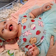 Melissa joined the competition — help win amazing prizes! baby, infant, smiling, child, clothing, headband, hand, blanket, tutu, pattern, cute, indoor, person, soft_toys, happy, lying_down, colorful, playful, fabric, portrait