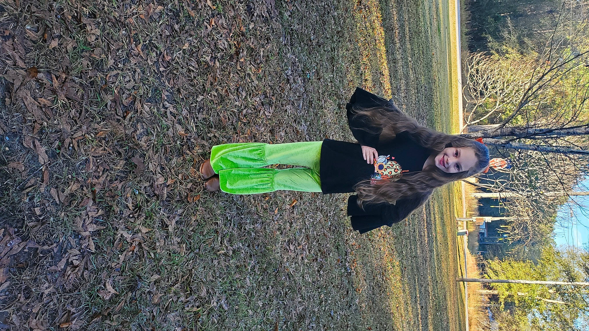 Daniella is registered to the contest to win money with this photo: active_pants, asphalt, footwear, fun, grass, jacket, joy, leisure, people_in_nature, person, plant, recreation, road_surface, shadow, soil, sweatpant, tar, tints_and_shades, tree, trunk