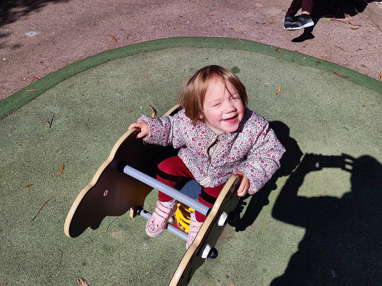 Lyla a rejoint le concours — aidez-le/la à gagner de superbes lots ! asphalt, child, city, facial_expression, grass, joy, leisure, people, people_in_nature, person, photograph, play, public_space, recreation, road_surface, shadow, sidewalk, sitting, smile, snapshot