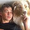 brown_and_white_dog, casual, closeup, companion, couch, dog, face, fluffy_dog, friendship, happy, human, indoor, light, pet, portrait, relaxed, resting, smiling_dog, striped_shirt, young_man