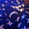 cat, tuxedo_cat, black_and_white, pet, sleeping, lying_down, upside_down, relaxed, blanket, star_pattern, blue_lighting, purple_lighting, indoor, home, cozy, whiskers, paws, fur, couch, cute