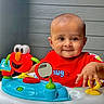 activity_center, baby, background, bright_colors, child, colorful, cute, expression, face, hand, happy, indoor, infant, mirror, person, play, red_shirt, smiling, toy, wood_paneling