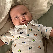 Asher joined the competition — help win amazing prizes! baby, infant, smiling, onesie, bed, blanket, clothing, cute, happy, child, face, lying_down, indoors, apparel, fabric, pattern, comfort, toddler, portrait, human