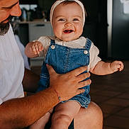 Rose participe au concours pour gagner de l'argent avec cette photo : baby, child, smile, denim_overalls, headband, adult, indoor, happy, person, holding, face, legs, hand, beard, casual_clothing, kitchen, refrigerator, warm_lighting, closeup, family