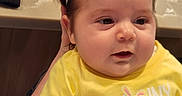Briiella-Rose is registered to the contest to win money with this photo: baby, bunny_design, cheeks, child, clothing, curly_hair, cute, expression, face, hand, headband, indoors, infant, person, portrait, sitting, skin, soft_lighting, yellow_shirt, young_child
