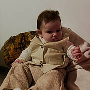 Lëyna participe au concours pour gagner de l'argent avec cette photo : baby, child, indoor, clothing, beige, cream, blanket, wooden_chair, curly_hair, face, portrait, sitting, shoes, long_pants, buttoned_vest, young_child, cute, soft_texture, casual, relaxed