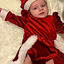 baby, infant, red_clothing, santa_hat, christmas_costume, festive, holiday, cute, portrait, lying_down, white_fur_trim, soft_texture, holiday_season, child, smiling, face, expressive_eyes, indoors, cozy, fluffy_background
