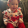 baby, barefoot, bow, child, clothing, comfortable, couch, cozy, cute, floral_clothing, happy, headband, home, indoors, infant, person, portrait, red_pants, sitting, smiling