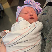 Esther is registered to the contest to win money with this photo: baby, blanket, bow, care, closeup, hand, hat, hospital, indoor, infant, nail_polish, newborn, person, pink, portrait, resting, sleeping, striped, swaddled, tattoo