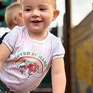 Estella is registered to the contest to win money with this photo: baby, blonde, bodypart, clothing, face, finger, hair, hand, happy, head, laughing, pants, person, photography, portrait, shirt, sitting, sleeve, smile, t_shirt