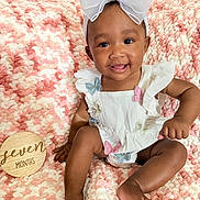 Melodie joined the competition — help win amazing prizes! baby, child, infant, smiling, white_bow, butterfly, headband, white_outfit, pink_blanket, textured_blanket, wooden_sign, seven_months, happy, cute, sitting, tongue_out, indoors, portrait, soft_texture, young_child